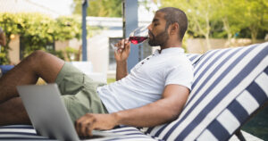Man drinking wine and using a laptop on FTTC NBN internet