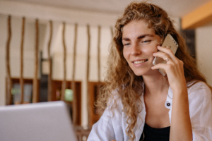 Happy blonde woman making a call on her unlocked Vodafone phone.
