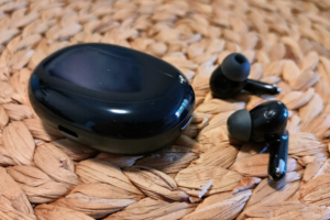 OPPO Enco X black wireless earbuds on a rattan placemat