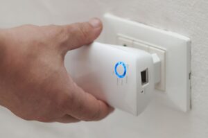 Photograph of man plugging in WiFi extender