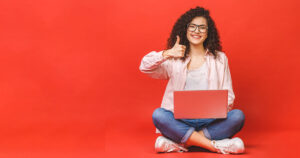 Photograph of a woman using a computer on a red background