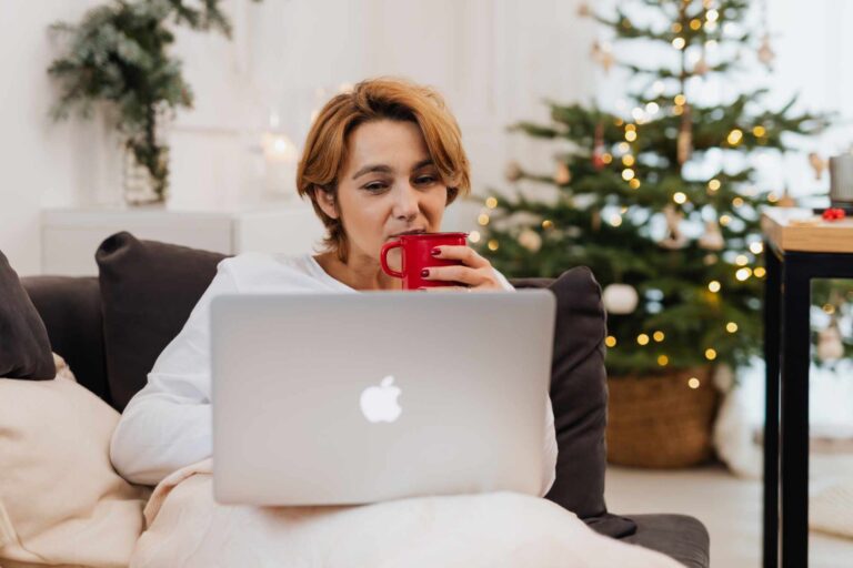 woman sipping coffee while at an apple laptop