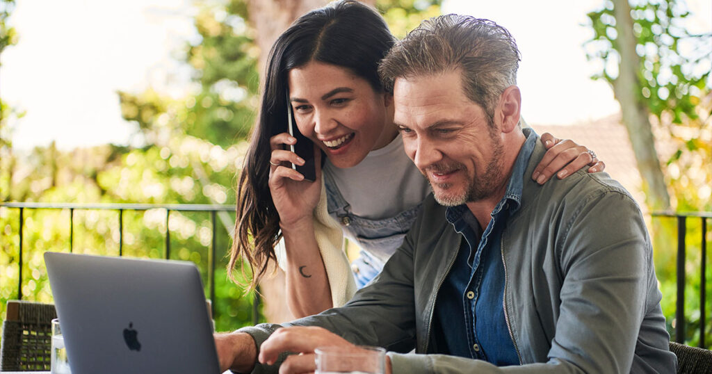 Photograph of a couple using a phone and laptop