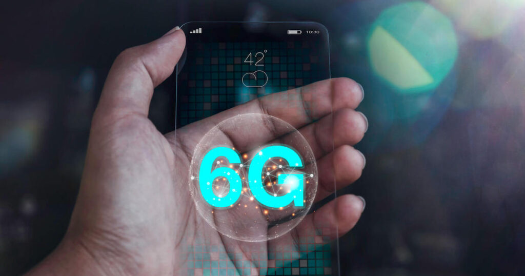 A hand holds a transparent phone with 6G on the screen