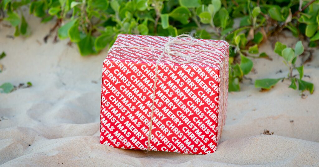 Best christmas gifts for Australians living overseas - a red present on a white sandy beach