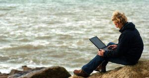 Photo of a man using mobile broadband to surf the internet at the beach