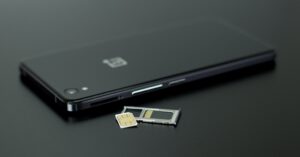 a black smartphone on a black table with a SIM card and SIM slot ready to activate