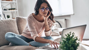 woman with glasses at laptop on couch
