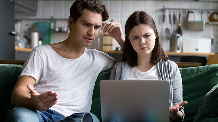 Couple looking at laptop with confused expressions
