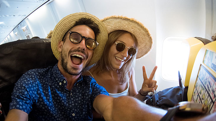 Man and woman inside plane smiling wearing hats