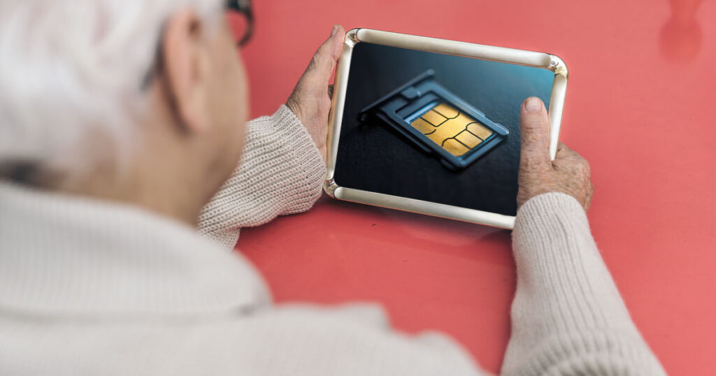 Photograph of an elderly woman looknig longingly upon a photograph of her old SIM card