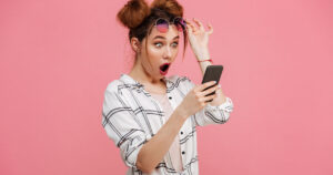 Stock photograph of a woman shocked by the activity occuring on her smartphone