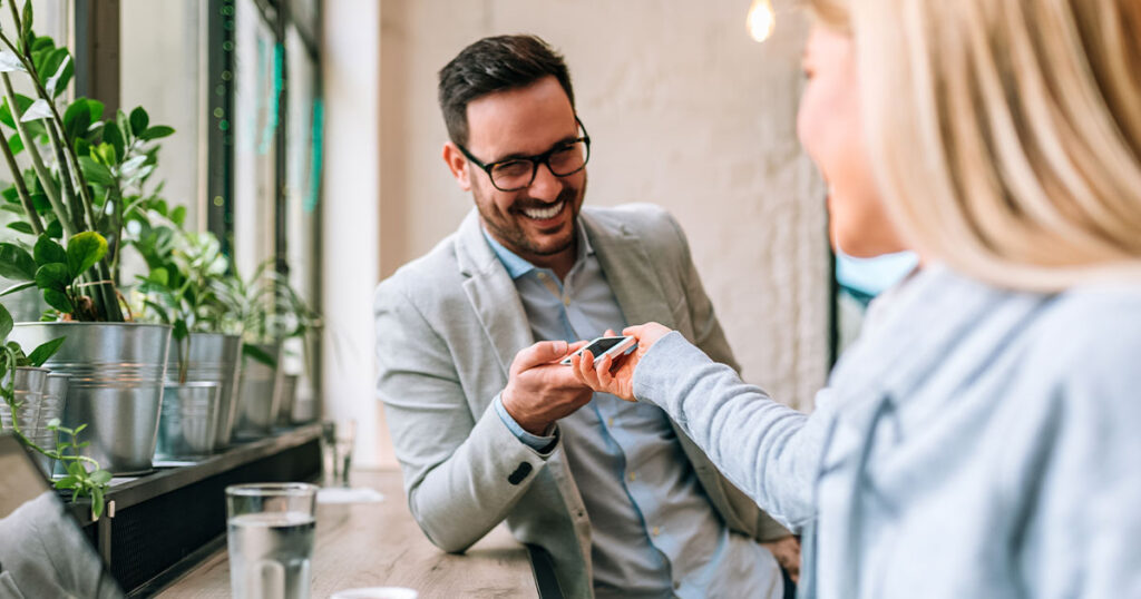 Photograph of two young professionals swapping phone numbers