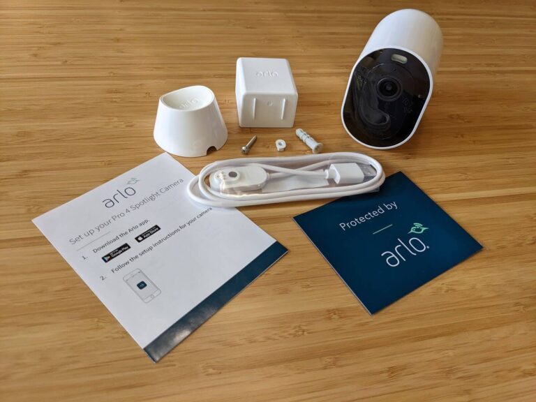 The Arlo Pro 4 camera and its charging wires, mounting equipment, and paper work sit on a table just out of the box