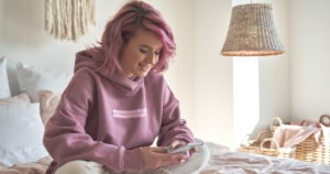Photograph of a woman with pink hair using her SIM-only plan on her smartphone