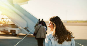 Photograph of a woman happily walking down the tarmac to board an airplane