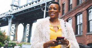 happy woman standing outside using cell phone