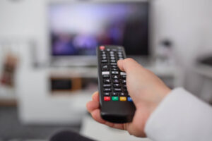 Person pointing cable TV remote to television