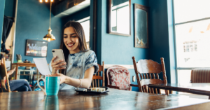 woman smiling at cell phone in a coffee shop
