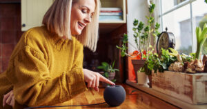Woman uses the buttons on the apple homepod mini