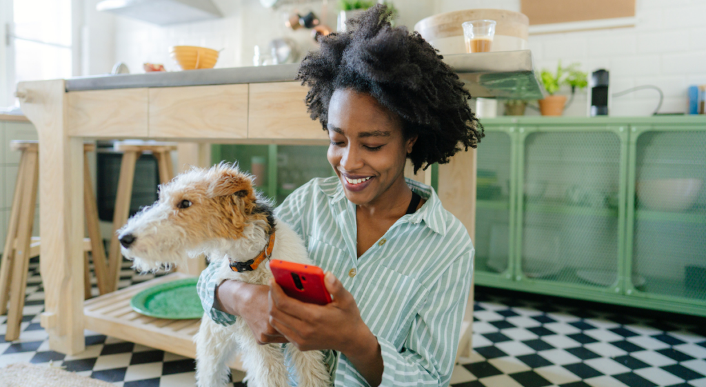 woman staring at cell phone in a kitchen while holding a dog