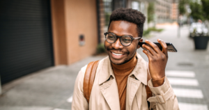 man happily listening to cell phone call while walking down the street