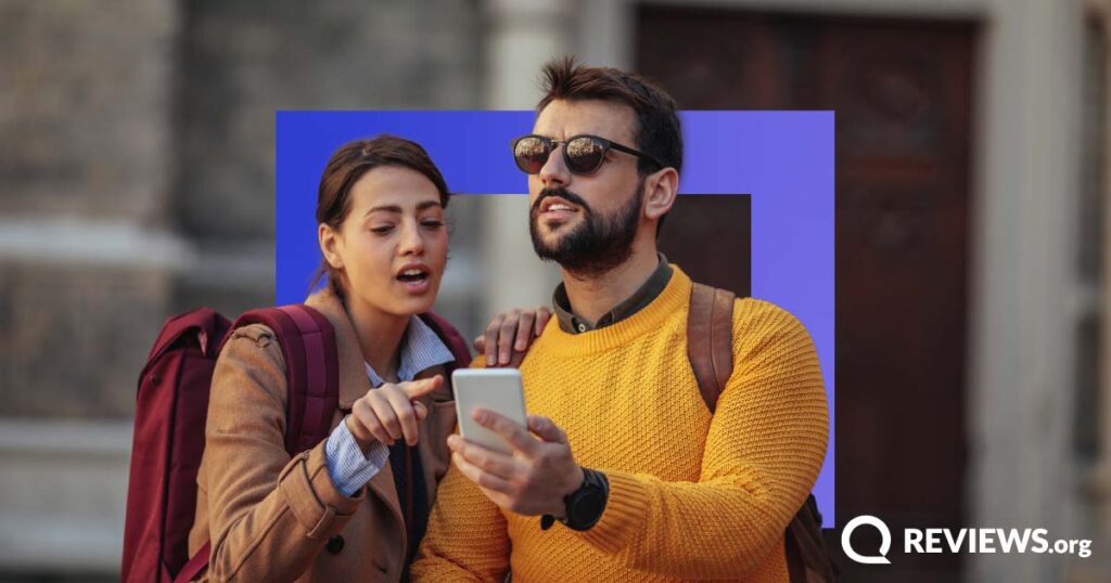 Man and a woman with backpacks look at a phone for directions