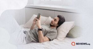male laying on bed using phone