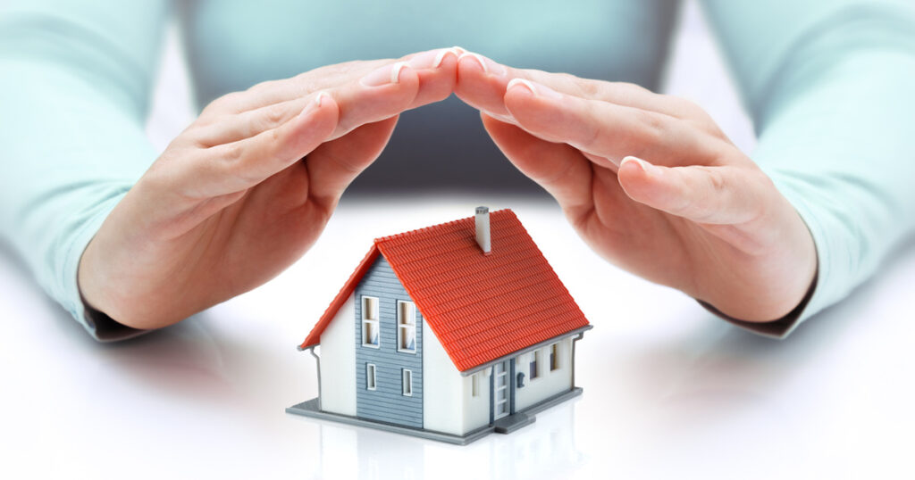 hands covering house - insurance concept - real estate