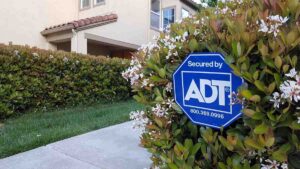 ADT sign in a bush near a driveway