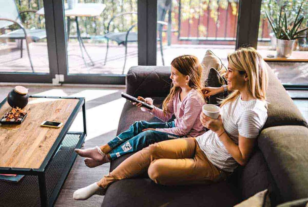 Mother and daughter watching TV on living room couch