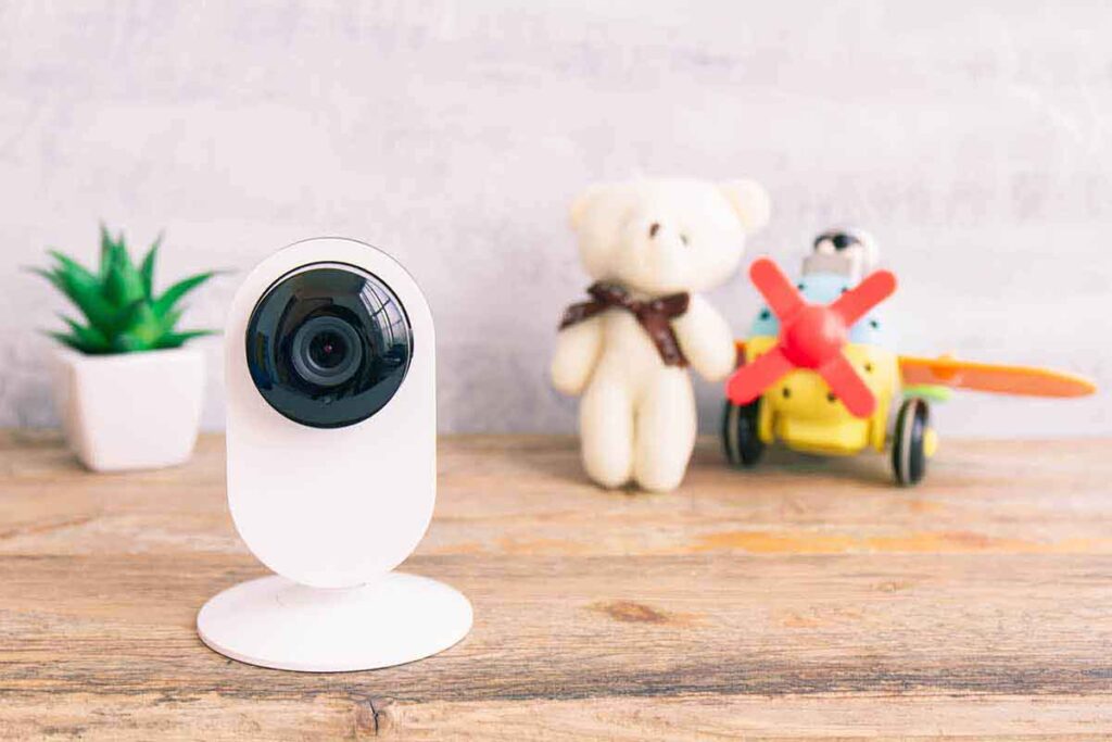 A white, rectangular security camera sitting on a wooden tabletop