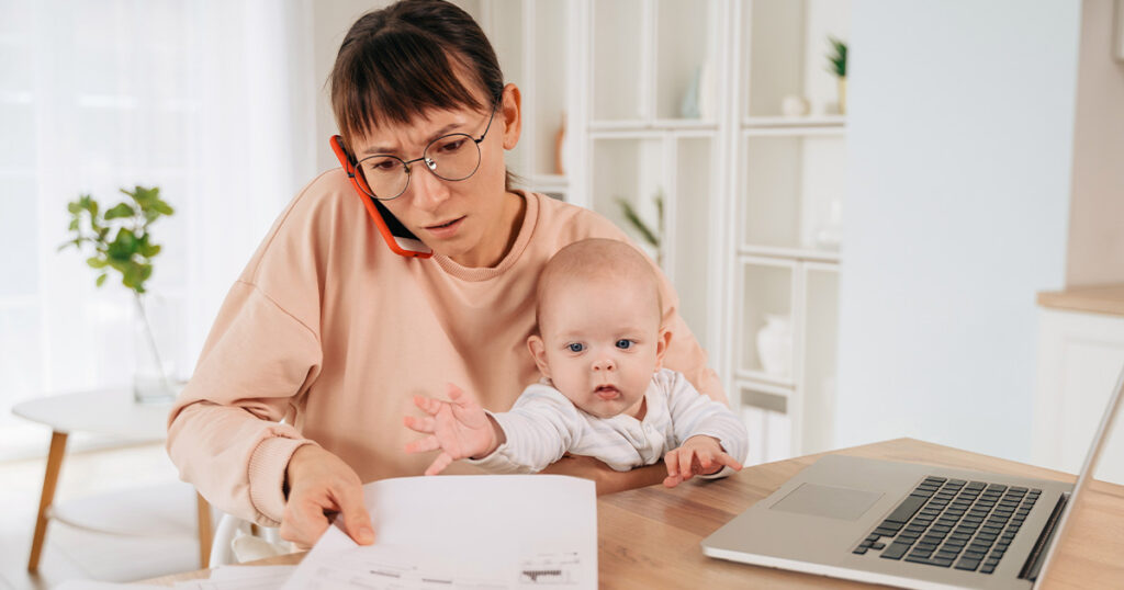 Photograph of a young mother and her baby stressed about money (the mother is stressed, the baby is blissfully unaware)