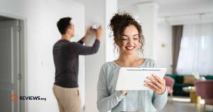 Happy female and partner setting up security system in light colored house