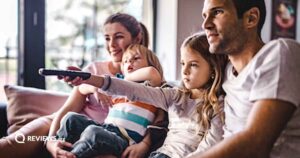 A mom, dad, pre-teen daughter and toddler son are all on the couch watching TV together