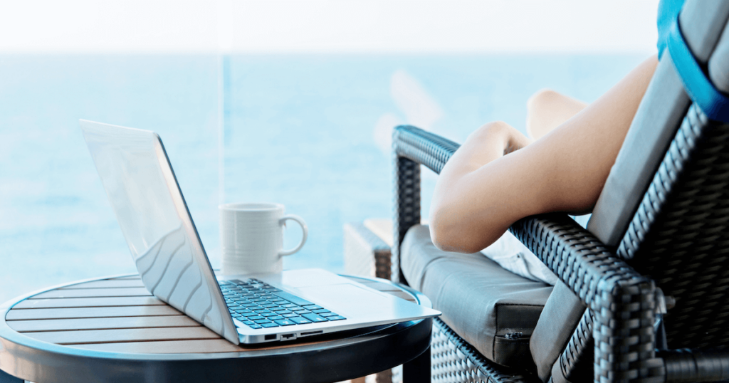 Image of a woman on the deck of a cruise ship with a laptop on a small table beside her