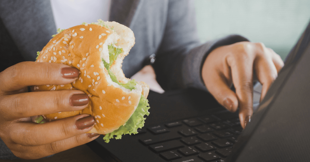 eating a burger while using a laptop