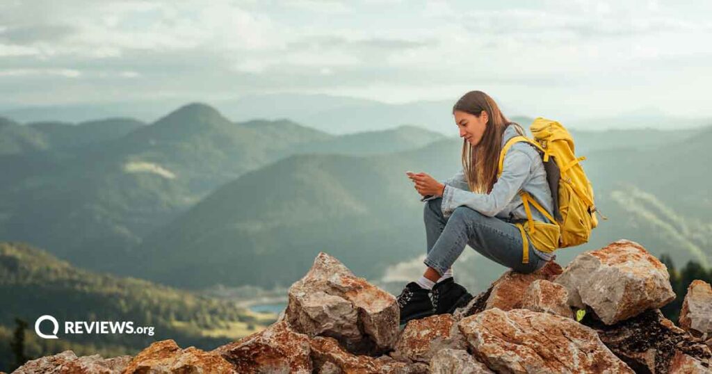 woman sitting on a rocky mountain using a cell phone