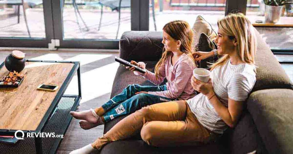 Mother and daughter watching TV on living room couch
