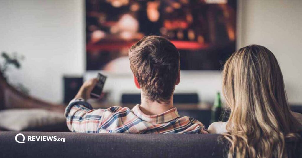 A young couple sitting on the couch in living room watching TV