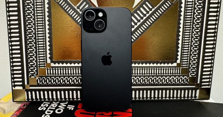 iPhone15 in black leaning against a gold and black vinyl