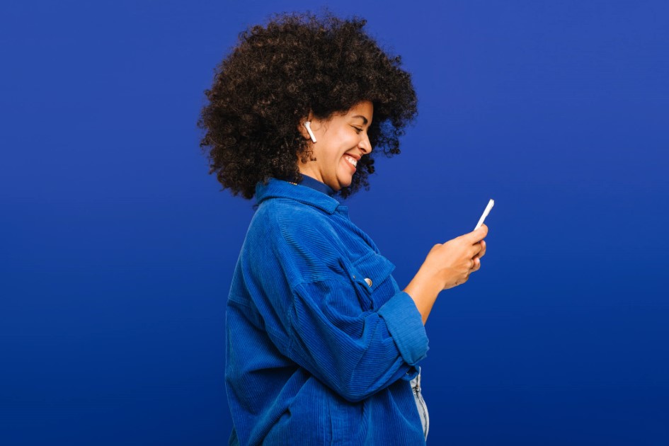 woman wearing blue looking and phone and smiling