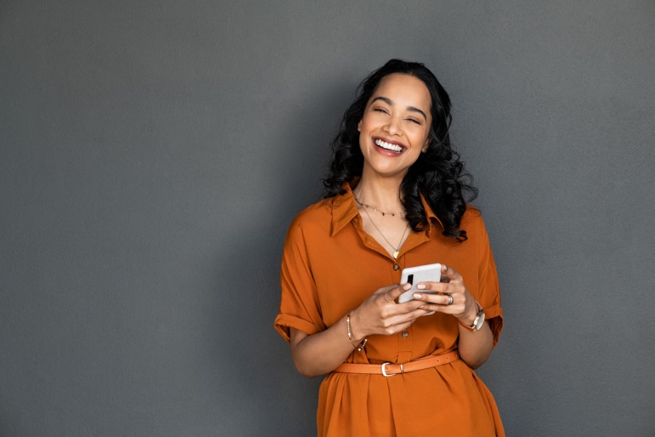 woman smiling while holding cell phone