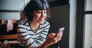 woman with short hair sitting on couch while using cell phone
