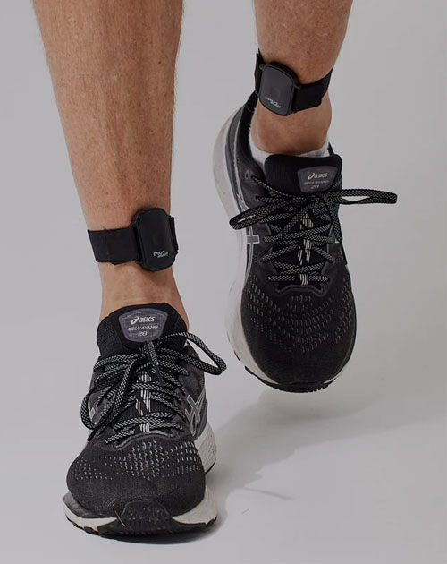 MVMT EVOLVE ankle monitor on male ankles while stepping towards the camera wearing black running shoes