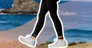 evolve mvmt ankle tracker on feminine legs, walking parallell to the camera on the coast