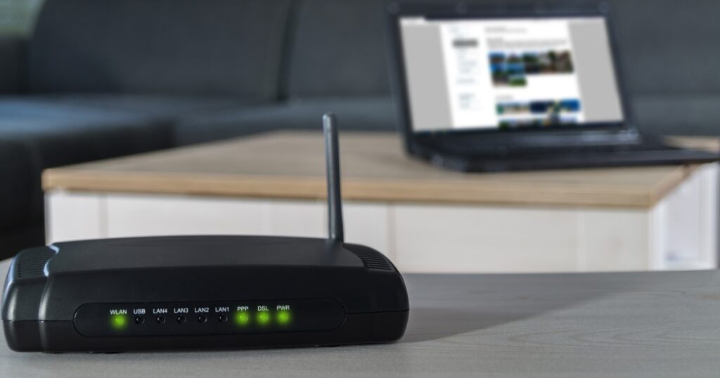 Image of internet modem in foreground with laptop in the background