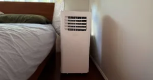 kogan 2.6kw portable aircon in the bedroom. nestled between the wall and a bed