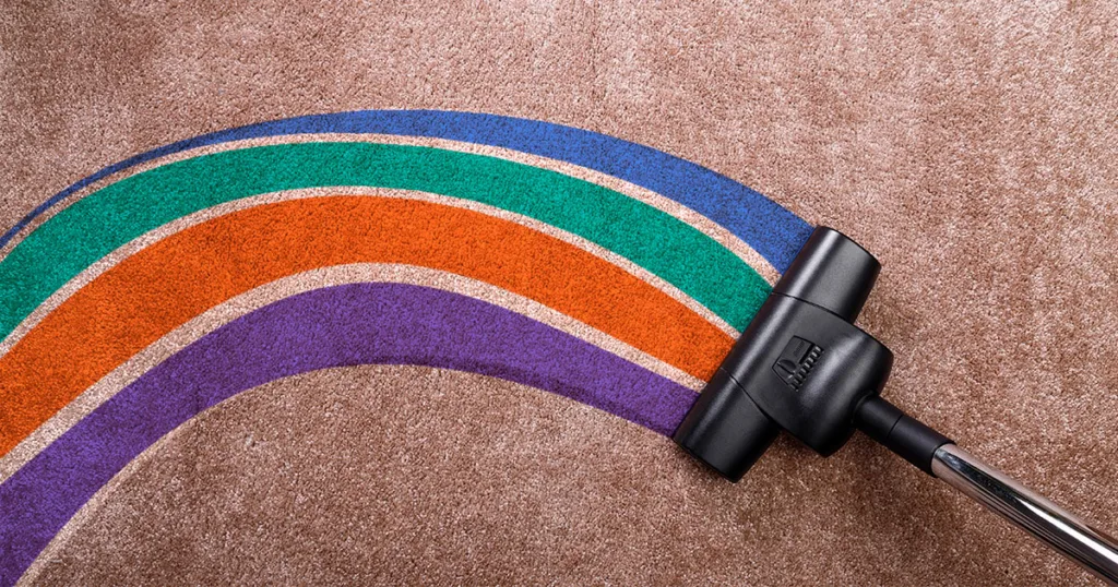 birds eye view of a stick vacuum on carpet with the vacuum line highlighted in purple, orange, green, and blue