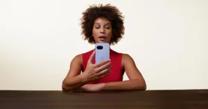 Google Pixel 9a being held by woman leaning on desk